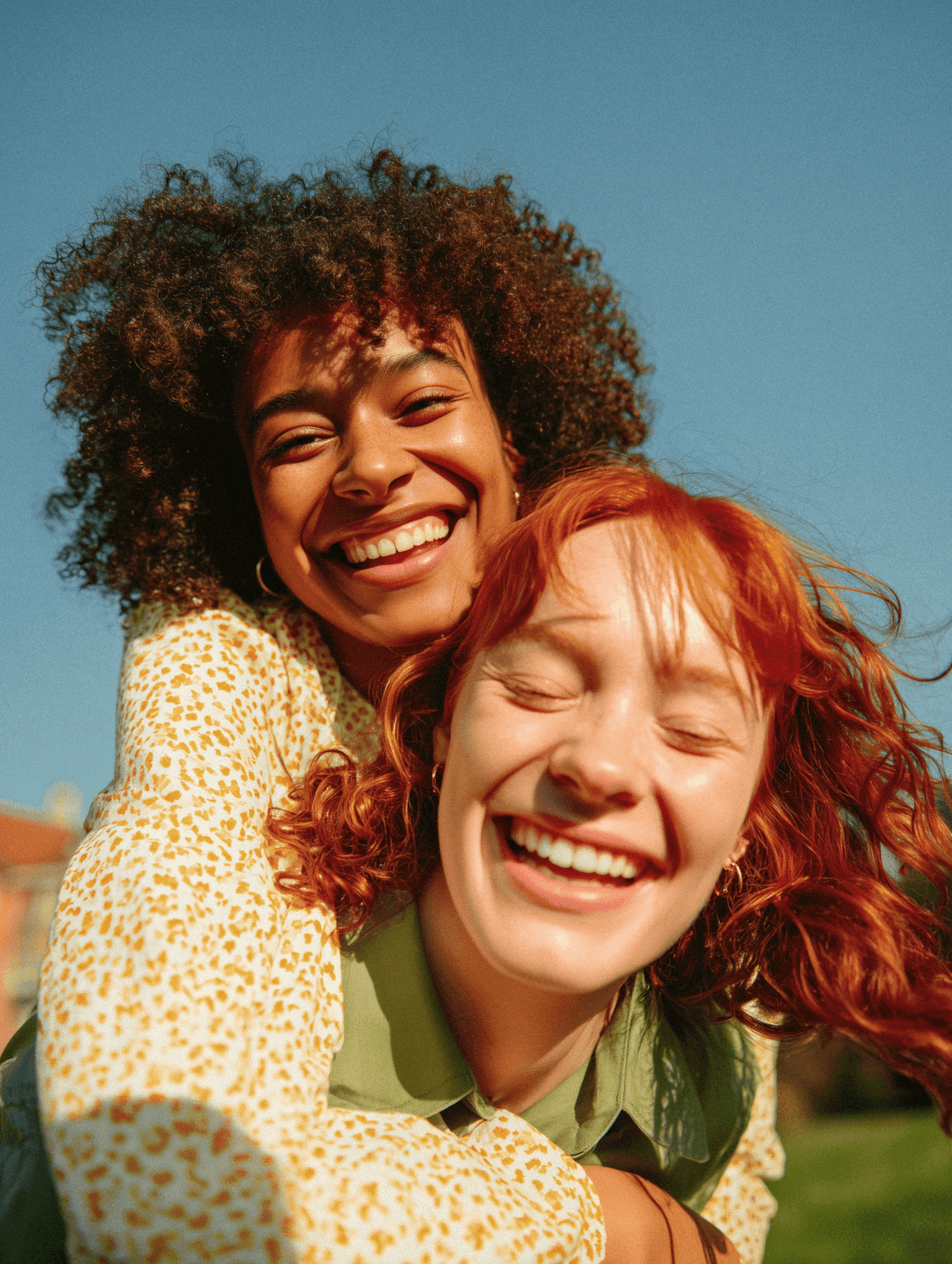 Two friends laughing together under a clear blue sky